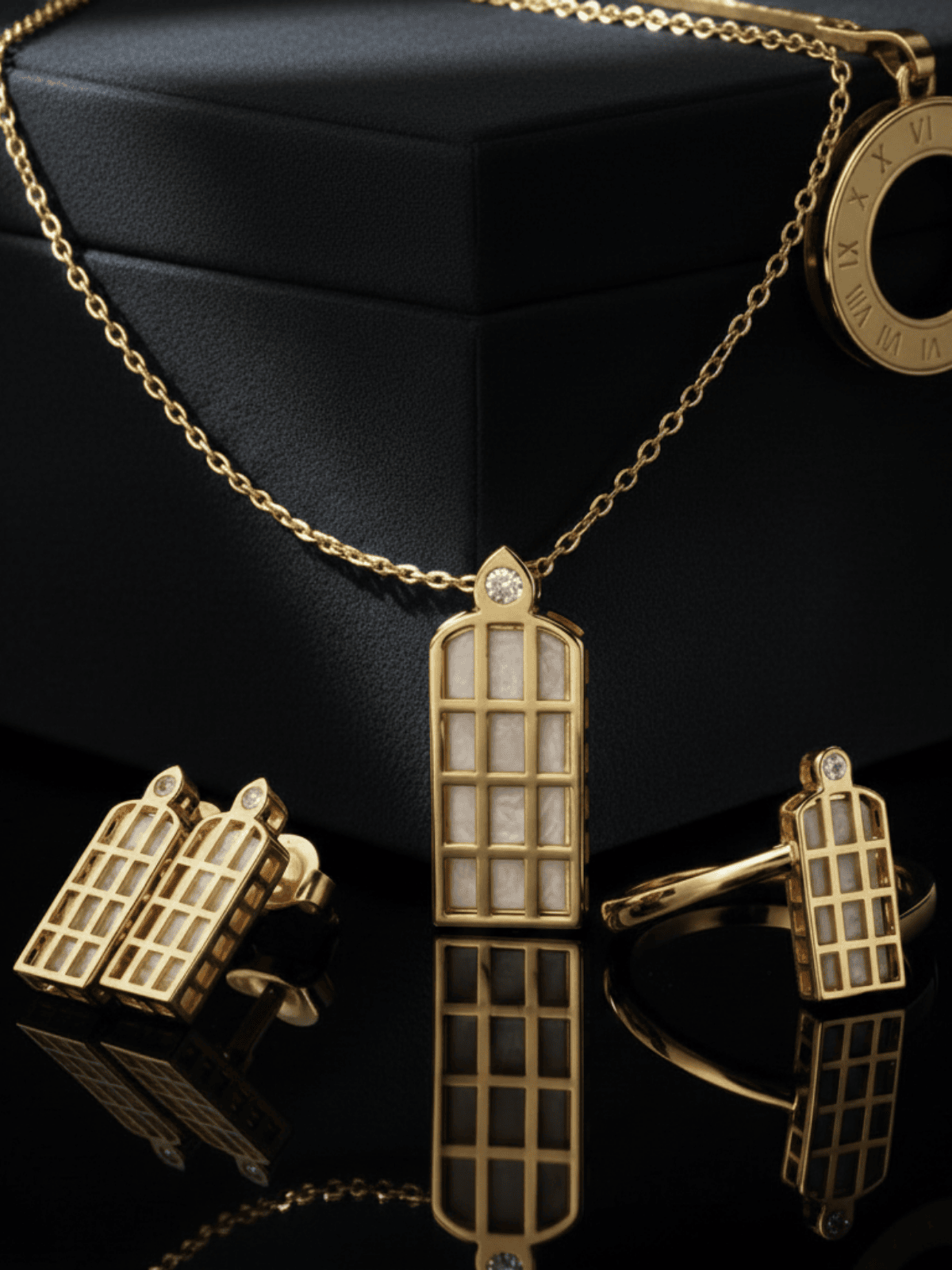 Zlatý náhrdelník LUMEN 14K v strede fotografie opretí o darčokvé balenie čiernej farby. Na pravo ja LUMEN prsteň z tej istej kolekcie a na ľavo sú LUMEN náušnice. Pohľad z boku