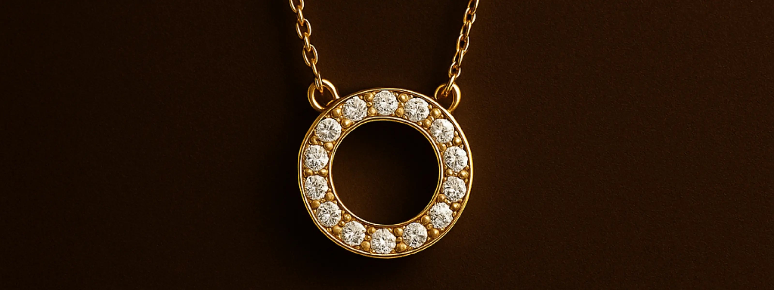 Zlatý náhrdelník s kruhovým príveskom osadeným čírymi kamienkami na tmavom pozadí