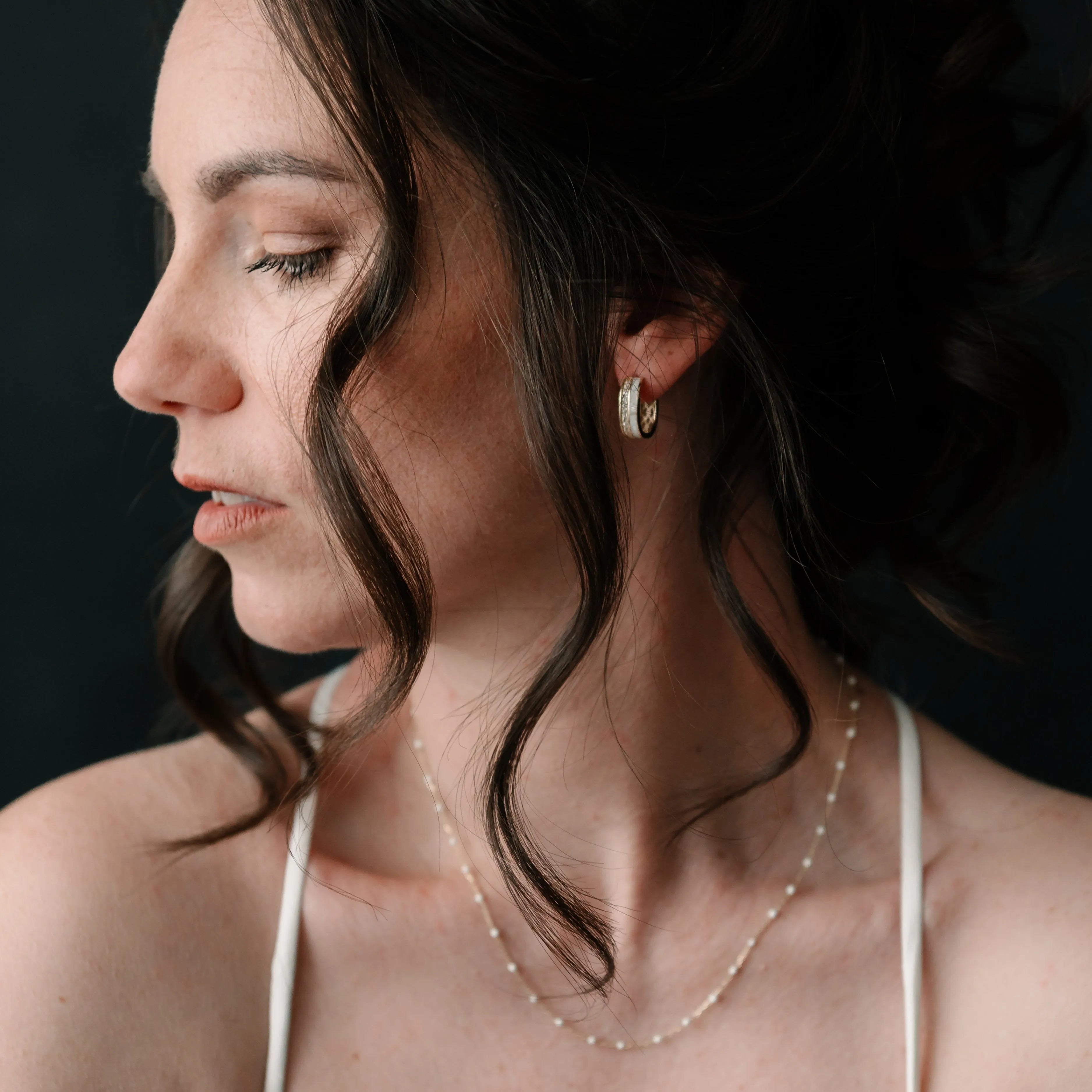 Elegantné zlaté náušnice CREYO Élégance GEOMETRIC na žene s kučeravými vlasmi