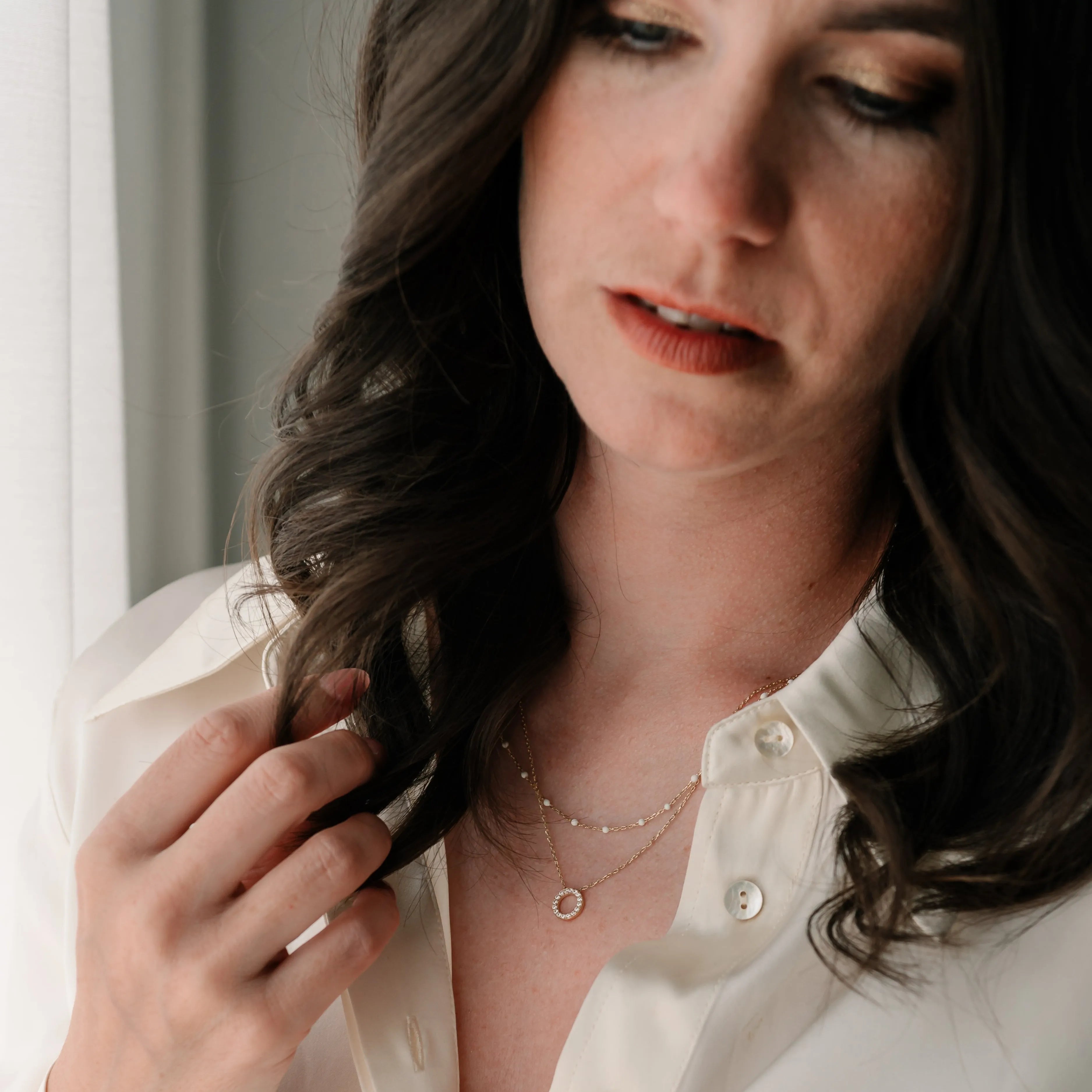 Žena v bielej blúzke nosí zlatý náhrdelník s okrúhlym príveskom – CREYO LINEA