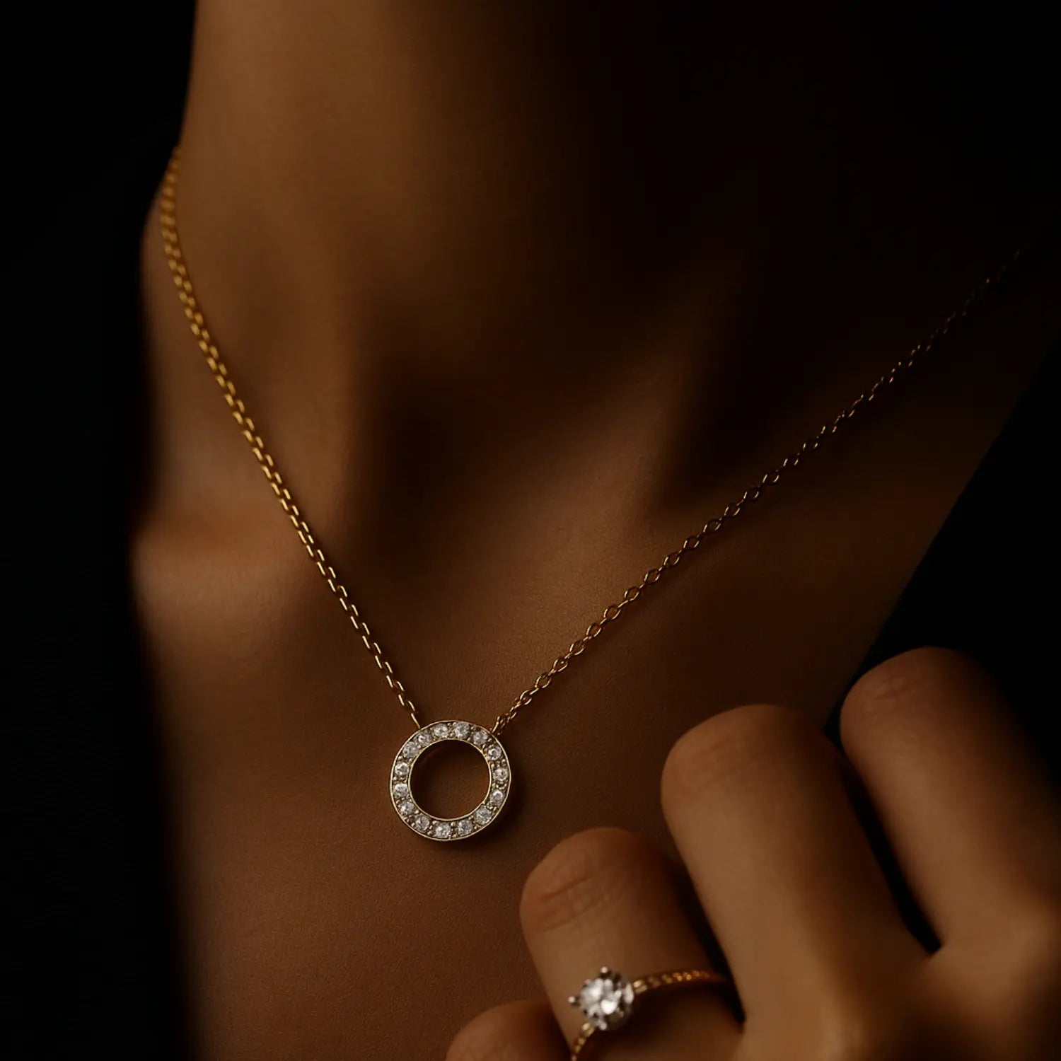 Zlatý náhrdelník s kruhovým príveskom s kamienkami na krku ženy na tmavom pozadí. Fotografia pre kolekciu náhrdelníkov.