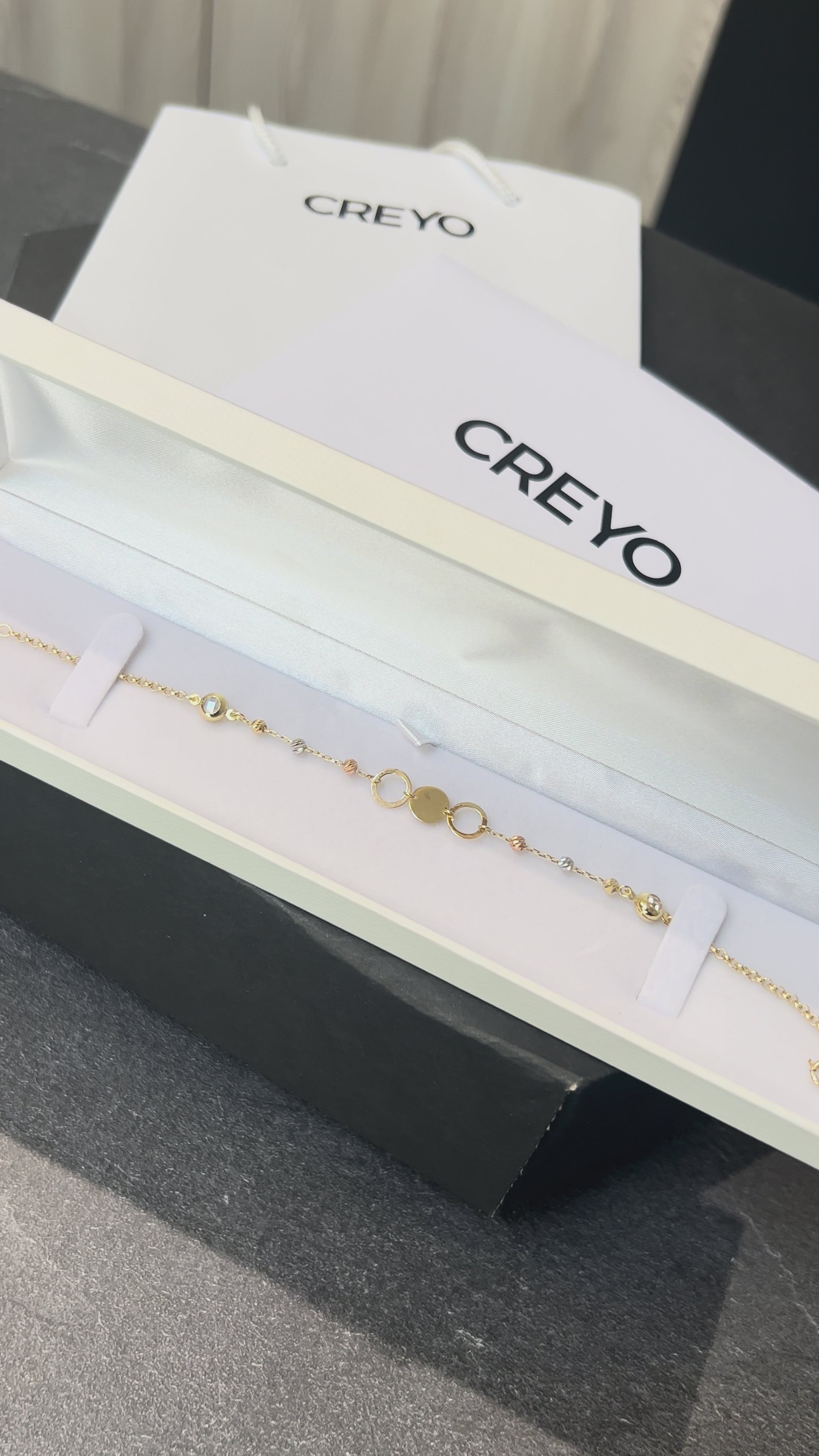 Detailné zábery na dámsky náramok CREYO AURELIA zo 14-karátového žltého zlata. Video ukazuje kombináciu plných a otvorených kruhových článkov zdobených čírymi kryštálmi. Náramok sa jemne leskne v mäkkom svetle a zvýrazňuje ženský, elegantný a moderný dizajn. Viditeľné je aj zapínanie typu pérový krúžok s predĺženou retiazkou, ktoré umožňuje prispôsobenie veľkosti.