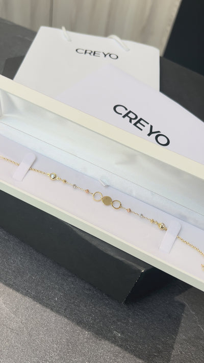 Detailné zábery na dámsky náramok CREYO AURELIA zo 14-karátového žltého zlata. Video ukazuje kombináciu plných a otvorených kruhových článkov zdobených čírymi kryštálmi. Náramok sa jemne leskne v mäkkom svetle a zvýrazňuje ženský, elegantný a moderný dizajn. Viditeľné je aj zapínanie typu pérový krúžok s predĺženou retiazkou, ktoré umožňuje prispôsobenie veľkosti.