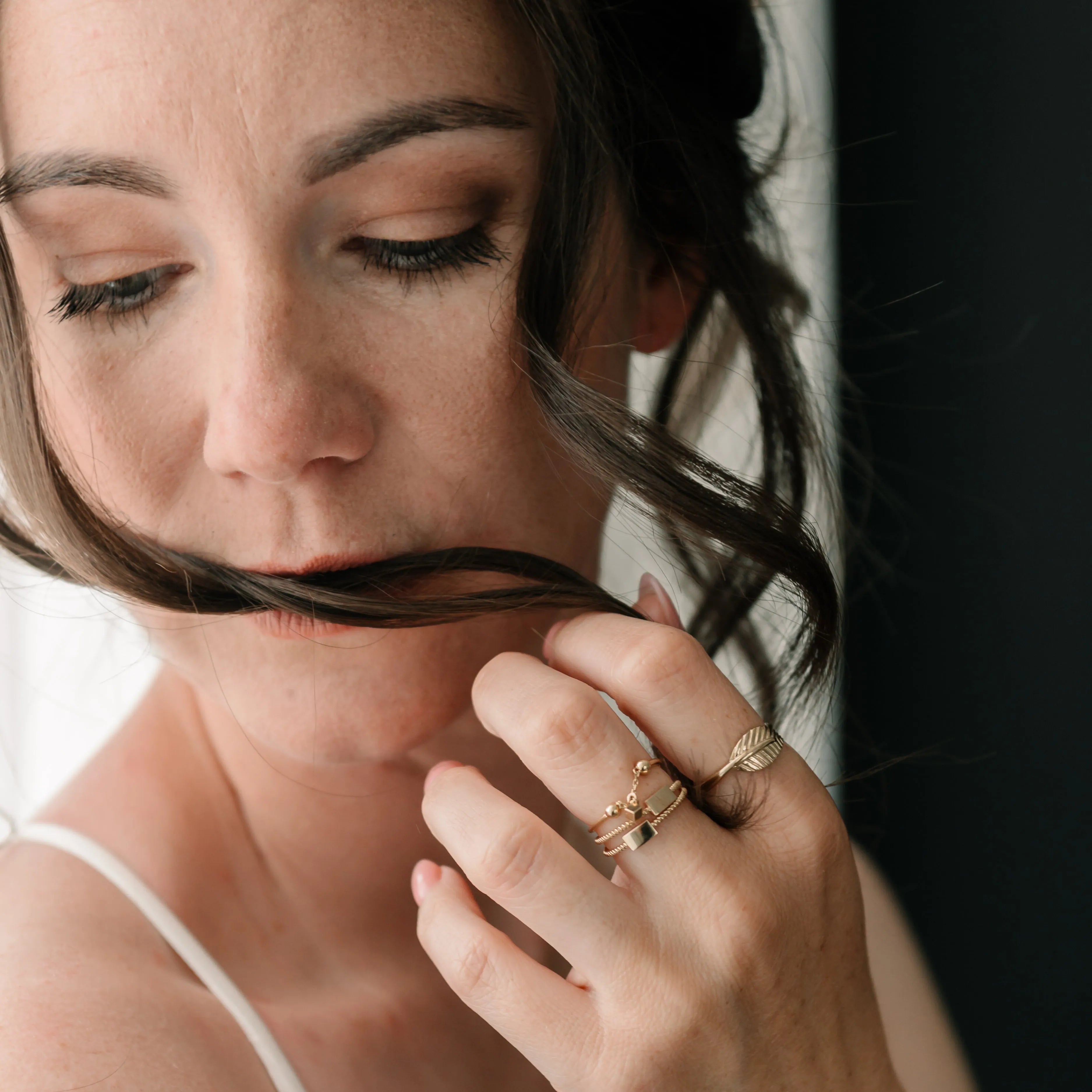 Elegantný prsteň s listovým motívom na ruke s viacerými zlatými prsteňmi